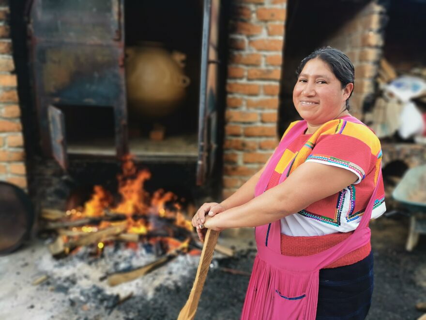 Juana junto al horno de leña donde cuece sus piezas